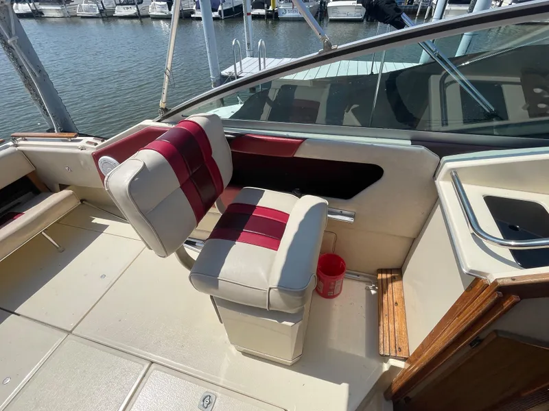 Slide: The Image of 1986 Sea Ray 268 Weekender boat interior with red and white seating at a marina. - 13