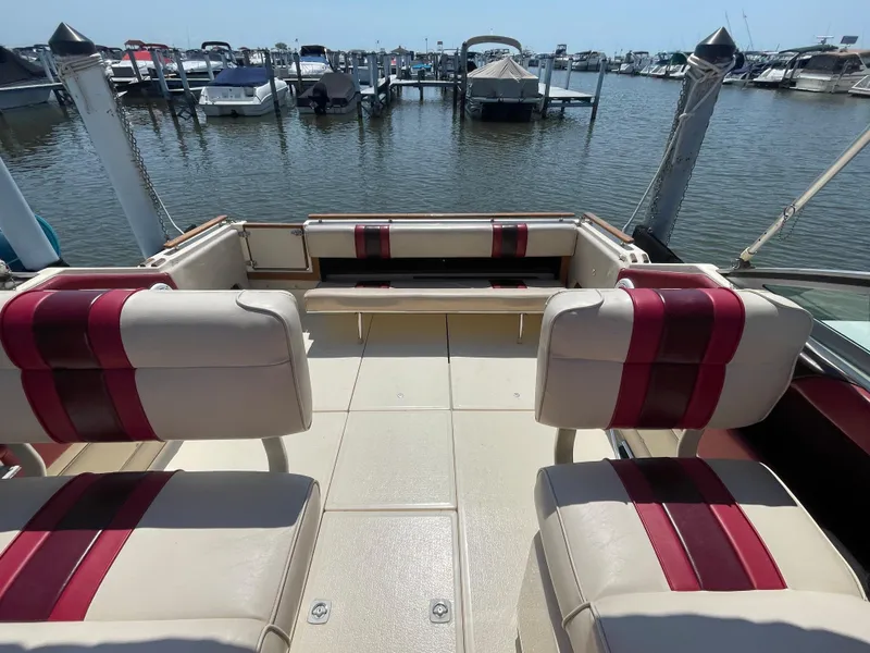 Slide: The Image of 1986 Sea Ray 268 Weekender boat interior with red and white seating at a marina. - 14