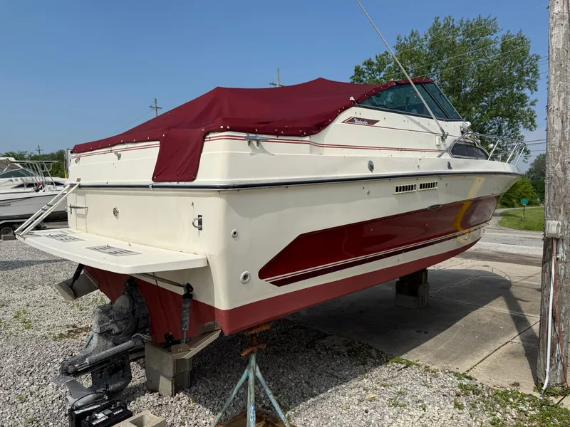 Slide: The Image of 1986 Sea Ray 268 Weekender boat with maroon cover, parked on gravel. - 3