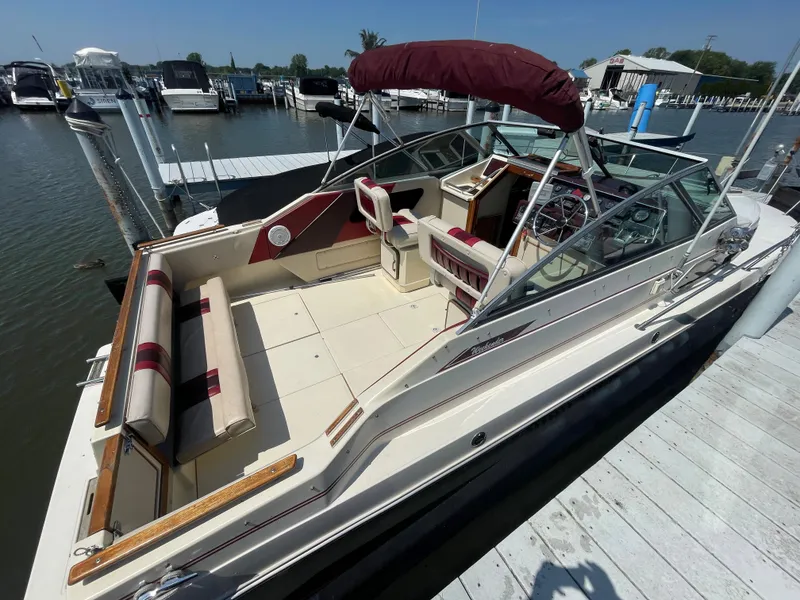 Slide: The Image of 1986 Sea Ray 268 Weekender boat docked, featuring spacious seating and maroon canopy. - 9
