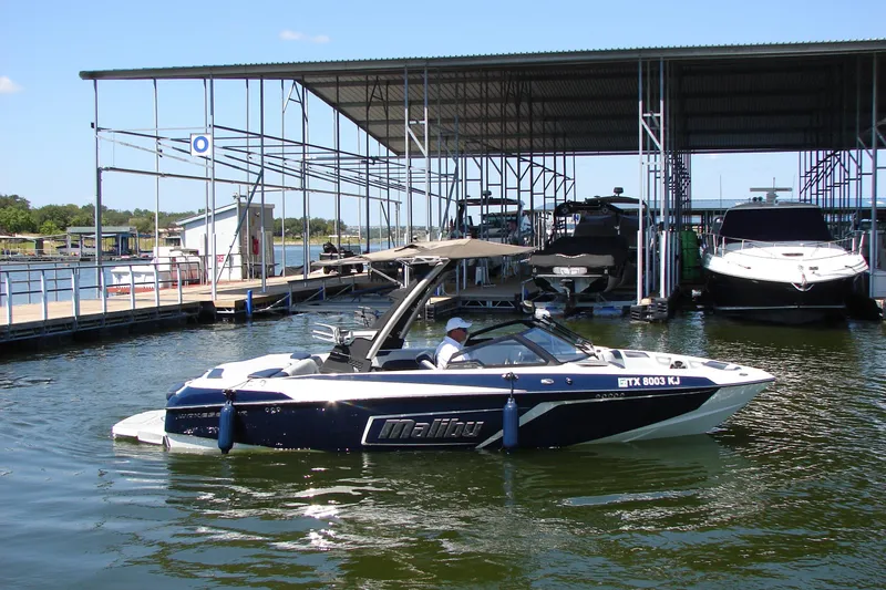 Slide: The Image of 2021 Malibu Wakesetter 22 LSV boat docked at a marina under a covered structure. - 14