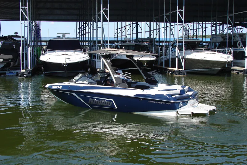Slide: The Image of 2021 Malibu Wakesetter 22 LSV boat docked in marina, surrounded by other vessels. - 18