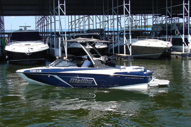 Slide: The Image of 2021 Malibu Wakesetter 22 LSV boat docked at a marina, surrounded by other boats. - 19