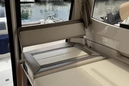 Slide: The Image of Interior seating of 2019 Cutwater C-24 Coupe boat, featuring beige upholstery and window view. - 28