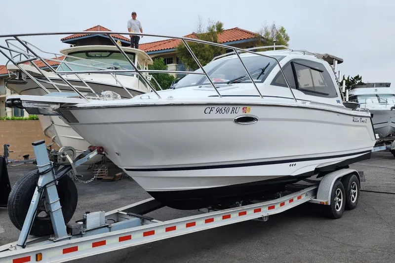 Slide: The Image of 2019 Cutwater C-24 Coupe boat on trailer, parked outdoors with houses in background. - 55