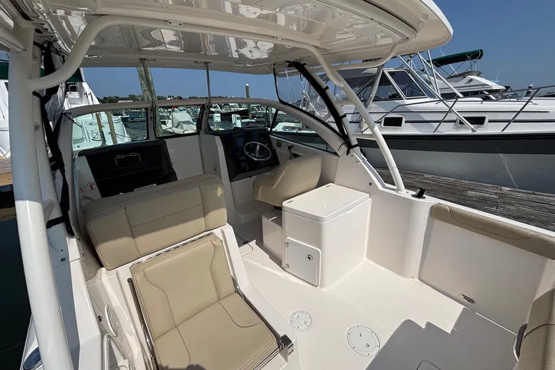 Slide: The Image of 2017 Pursuit DC 235 Dual Console boat interior with beige seating and helm, docked at marina. - 15