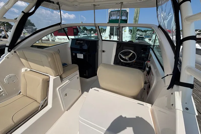 Slide: The Image of 2017 Pursuit DC 235 Dual Console boat interior with beige seating and steering wheel. - 16