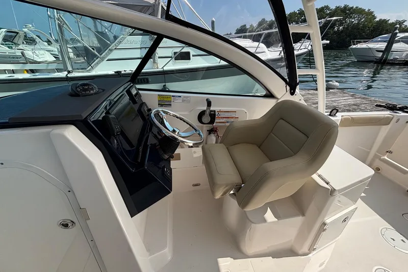Slide: The Image of 2017 Pursuit DC 235 Dual Console boat interior with helm, steering wheel, and captain's chair. - 17