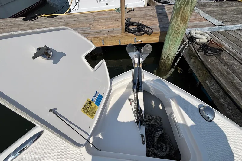 Slide: The Image of 2017 Pursuit DC 235 Dual Console anchor compartment at dock, open hatch, visible ropes. - 23