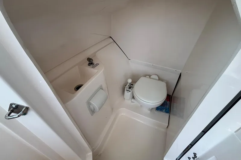 Slide: The Image of 2017 Pursuit DC 235 Dual Console boat bathroom with toilet and sink. - 24