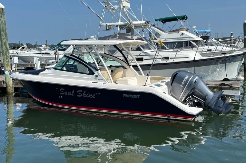 Slide: The Image of 2017 Pursuit DC 235 Dual Console boat docked in marina, featuring Yamaha outboard motor. - 5