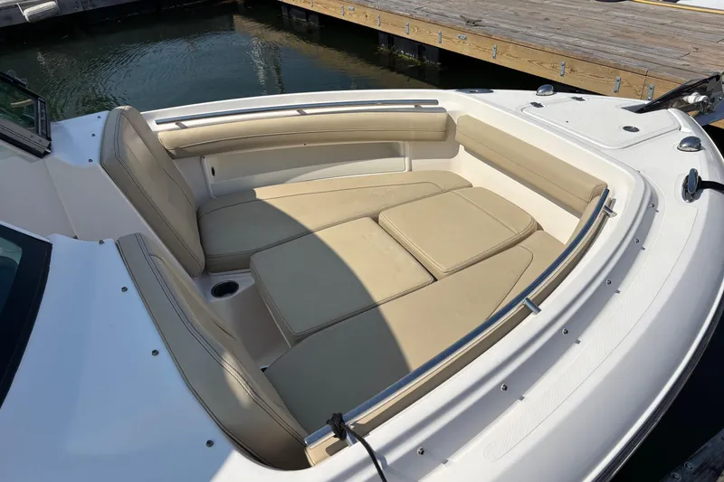 Slide: The Image of 2017 Pursuit DC 235 Dual Console boat with beige seating, docked by wooden pier. - 8