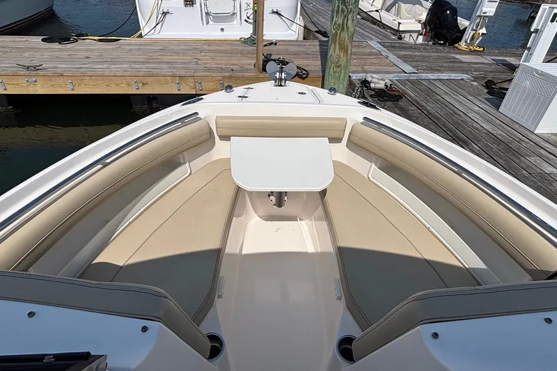 Slide: The Image of 2017 Pursuit DC 235 Dual Console boat interior with seating and table at dock. - 9