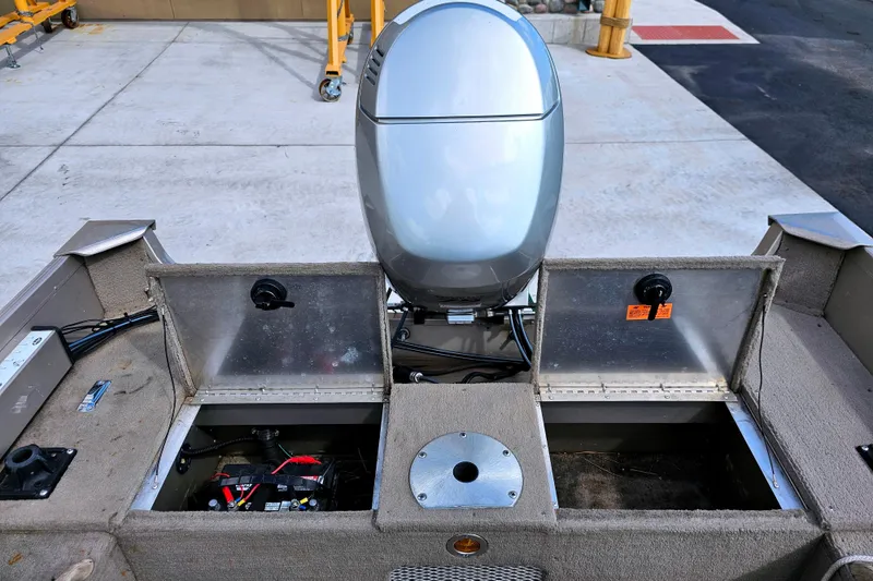 Slide: The Image of 2000 Alumacraft Navigator 165 CS boat interior with open storage compartments and motor. - 24