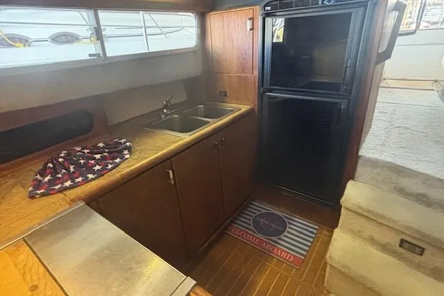 Slide: The Image of 1990 Bayliner 3888 yacht kitchen with sink, fridge, and wooden cabinetry. - 11