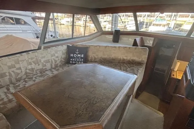 Slide: The Image of Interior of 1990 Bayliner 3888 yacht with dining area and marina view. - 14