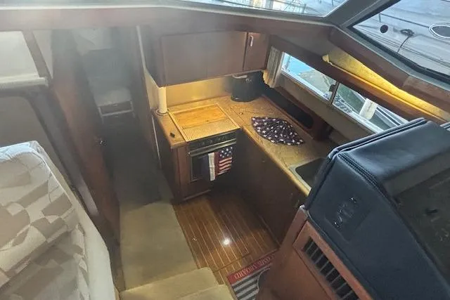 Slide: The Image of 1990 Bayliner 3888 yacht interior with compact kitchen and wooden flooring. - 15