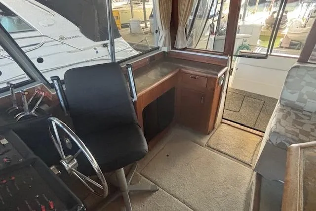 Slide: The Image of 1990 Bayliner 3888 boat interior with helm, steering wheel, and seating area. - 16
