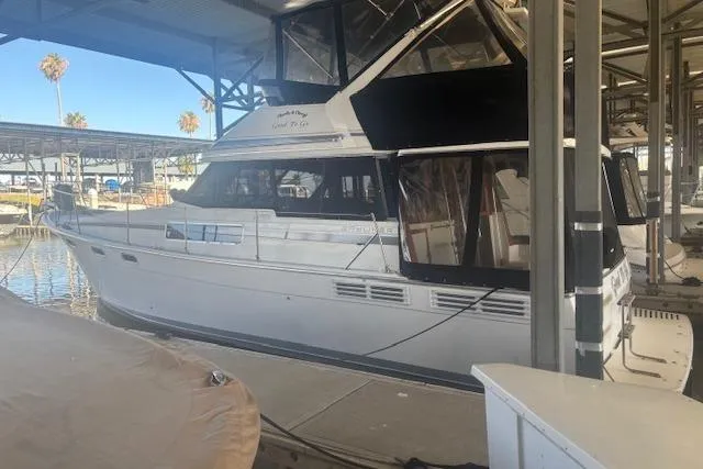 Slide: The Image of 1990 Bayliner 3888 yacht docked in a marina under a covered structure. - 2