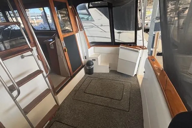 Slide: The Image of 1990 Bayliner 3888 boat interior with carpeted floor, wooden accents, and steps leading to cabin. - 22