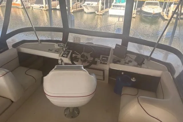 Slide: The Image of 1990 Bayliner 3888 boat interior with helm, steering wheel, and seating at marina. - 23