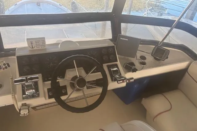 Slide: The Image of 1990 Bayliner 3888 boat helm with steering wheel, controls, and navigation equipment. - 24