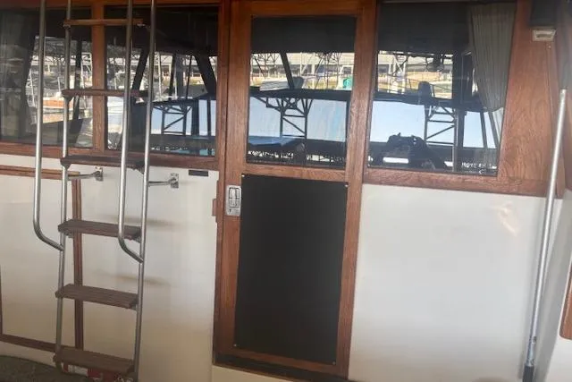 Slide: The Image of 1990 Bayliner 3888 boat interior with wooden door and ladder, marina view. - 3
