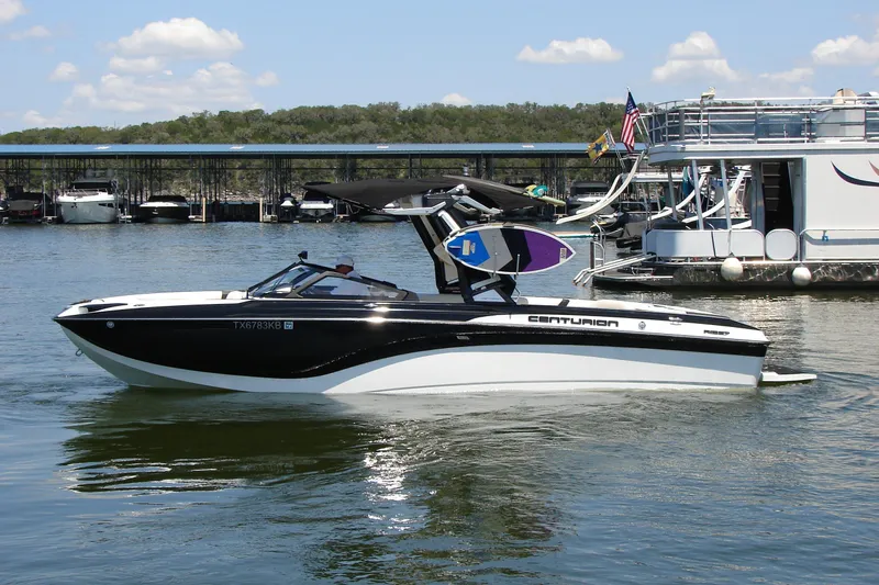 Slide: The Image of 2019 Centurion Ri257 boat on a sunny lake, docked near other vessels. - 0