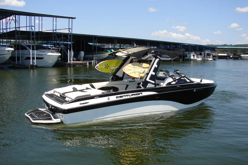 Slide: The Image of 2019 Centurion Ri257 boat docked with surfboards, under clear blue sky. - 11