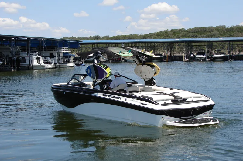 Slide: The Image of 2019 Centurion Ri257 boat on a lake near a marina, with wakeboards mounted. - 14