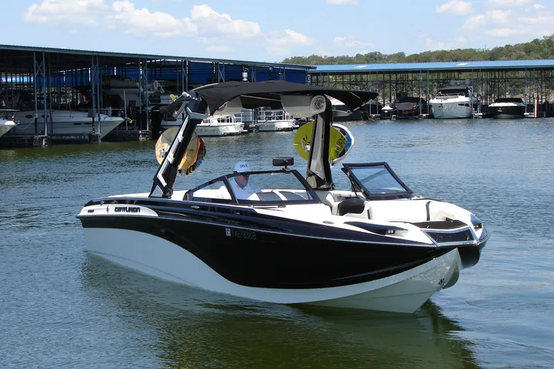 Slide: The Image of 2019 Centurion Ri257 boat on water near marina, featuring sleek black and white design. - 6