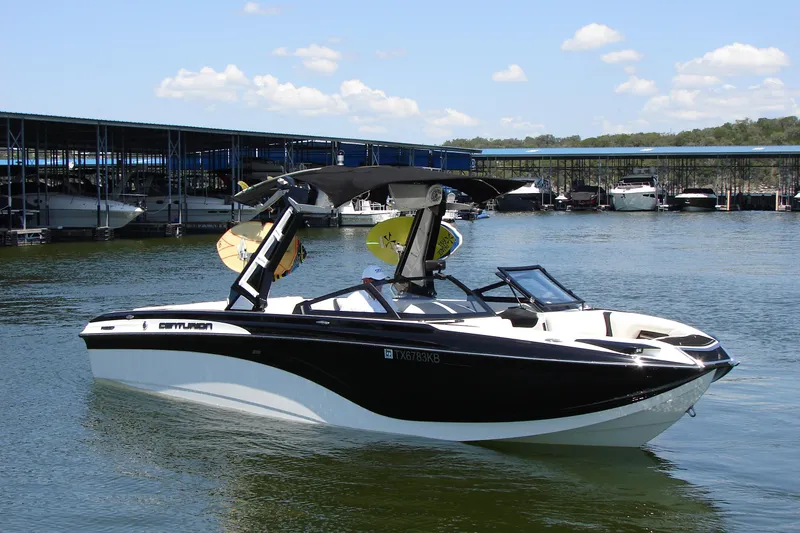 Slide: The Image of 2019 Centurion Ri257 boat docked on a sunny day, featuring sleek black and white design. - 7