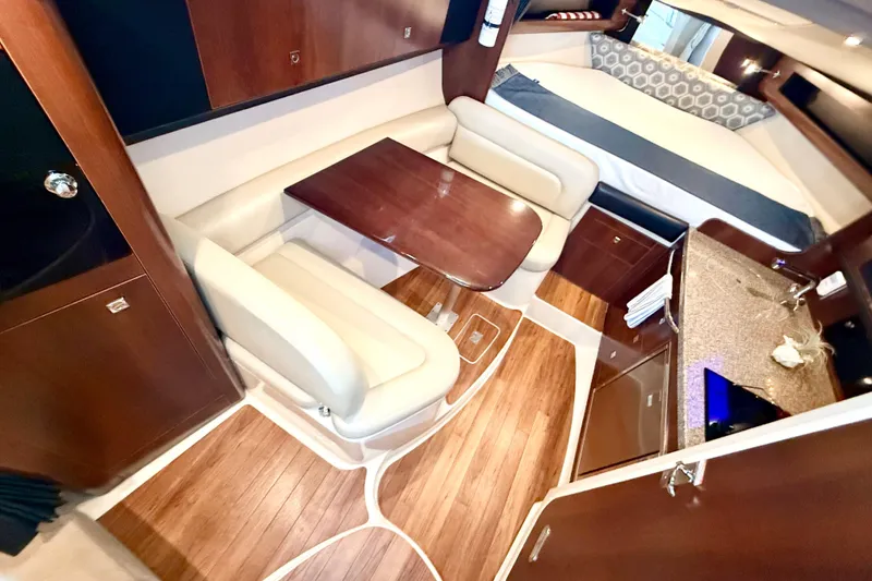 Slide: The Image of 2016 Chaparral 290 Signature interior with dining area, kitchenette, and bed. Luxurious wood finish. - 18