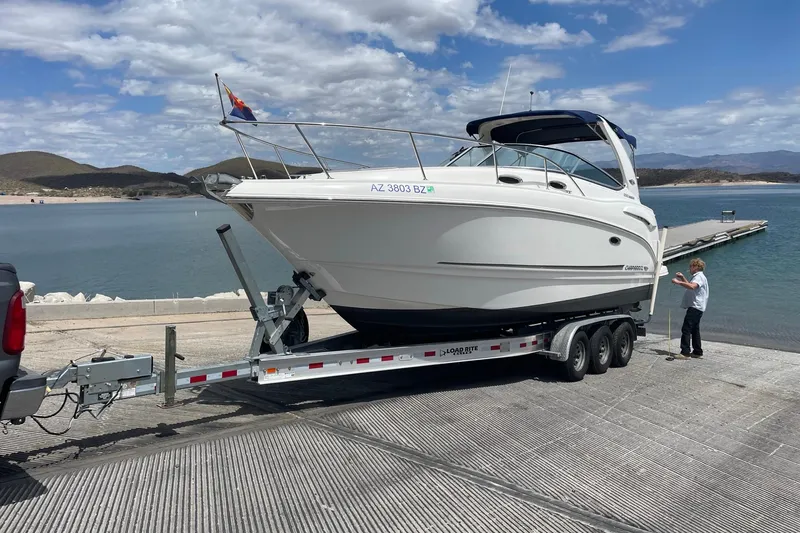Slide: The Image of 2016 Chaparral 290 Signature boat on trailer by lake, clear sky, person nearby. - 42