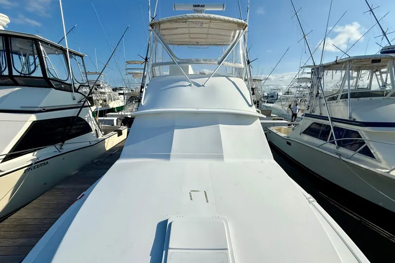 Slide: The Image of 1979 Bertram 35 Flybridge yacht docked among other boats under a clear blue sky. - 12