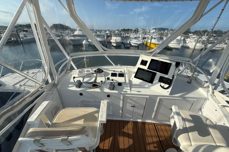 Slide: The Image of 1979 Bertram 35 Flybridge helm with marina view, featuring navigation equipment and seating. - 19