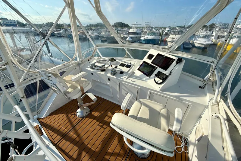 Slide: The Image of 1979 Bertram 35 Flybridge helm with modern controls, overlooking marina. - 21