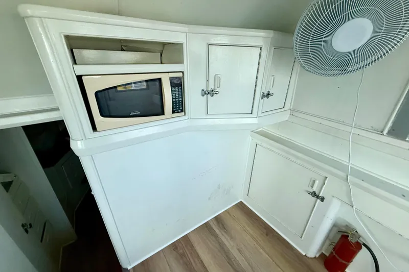 Slide: The Image of 1979 Bertram 35 Flybridge interior with microwave, cabinets, fan, and fire extinguisher. - 26