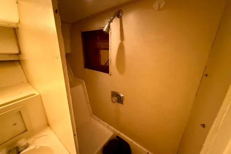 Slide: The Image of 1979 Bertram 35 Flybridge bathroom with shower and sink, featuring beige interior. - 32