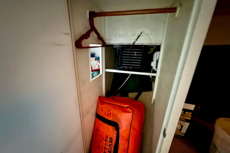 Slide: The Image of 1979 Bertram 35 Flybridge interior storage with orange life raft and hangers. - 38