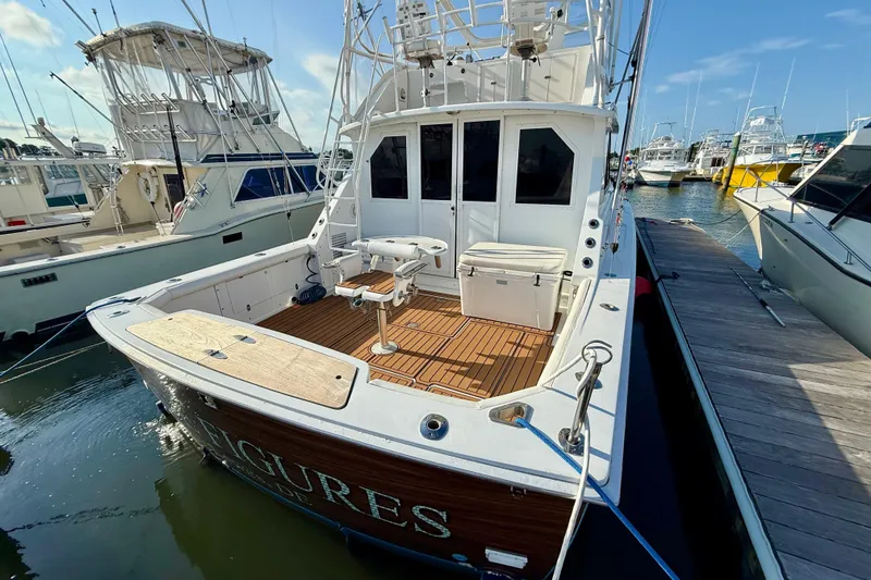 Slide: The Image of 1979 Bertram 35 Flybridge boat docked, featuring spacious deck and fishing chair. - 4