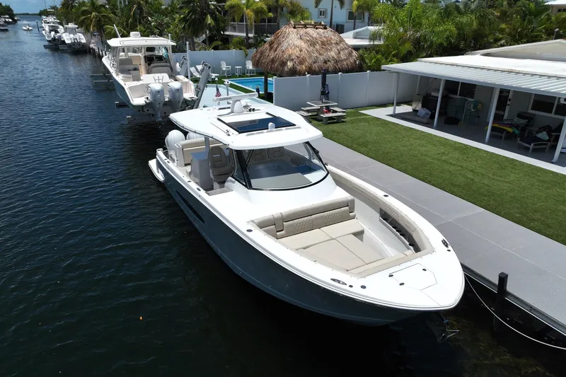 Slide: The Image of 2022 Regal 38 SAV boat docked by a waterfront home with lush greenery. - 2