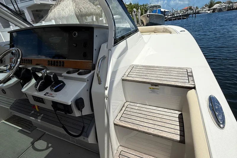 Slide: The Image of 2022 Regal 38 SAV boat helm with controls and steps, docked by the water. - 29