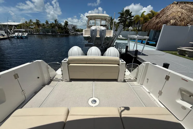 Slide: The Image of 2022 Regal 38 SAV boat interior with seating, docked by a marina under a clear sky. - 3