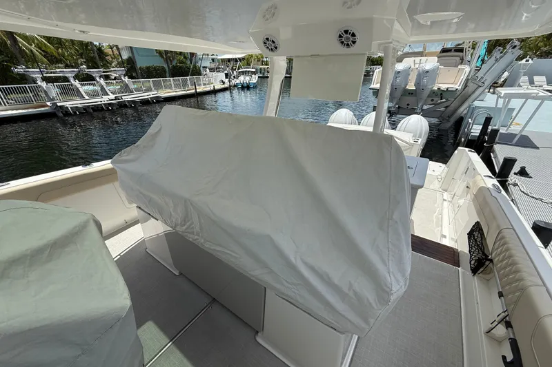 Slide: The Image of 2022 Regal 38 SAV boat interior with covered seating, docked by the water. - 35