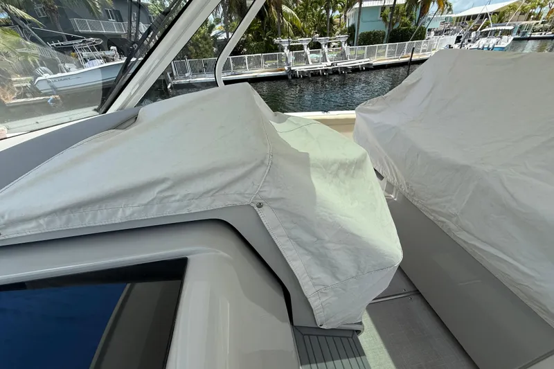 Slide: The Image of 2022 Regal 38 SAV boat interior with protective covers, docked near waterfront homes. - 36