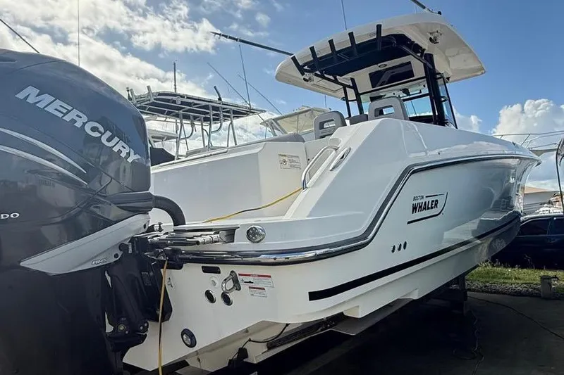 The Image of 2023 Boston Whaler 330 Outrage boat with Mercury engine, docked under a blue sky. - 1