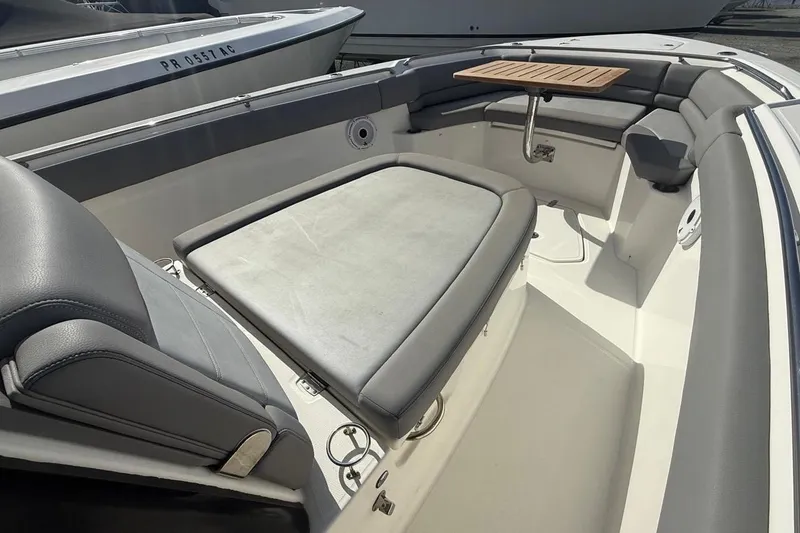 Slide: The Image of 2023 Boston Whaler 330 Outrage interior with cushioned seating and wooden table. - 15