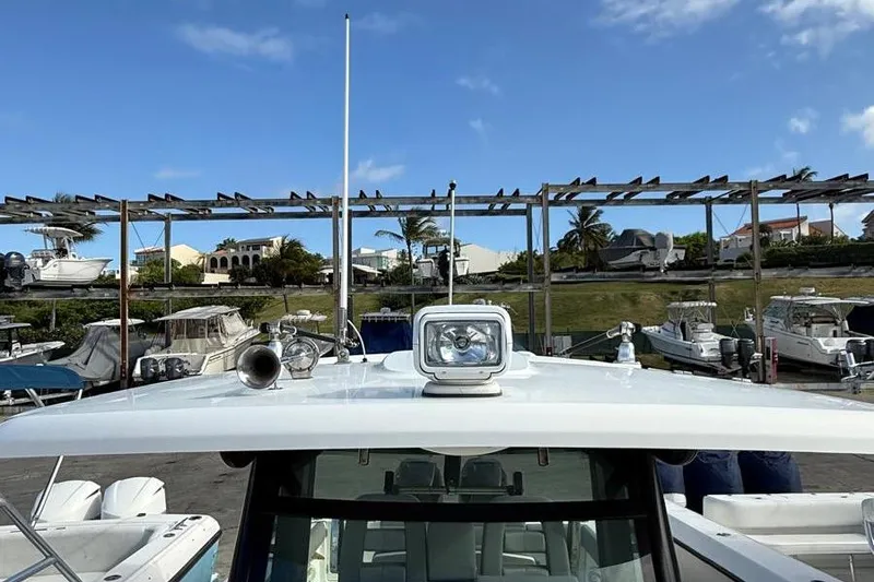 Slide: The Image of 2023 Boston Whaler 330 Outrage boat docked, featuring spotlight and horn on deck. - 18
