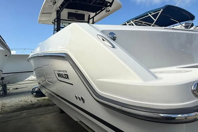 Slide: The Image of 2023 Boston Whaler 330 Outrage boat, sleek design, docked under clear blue sky. - 3